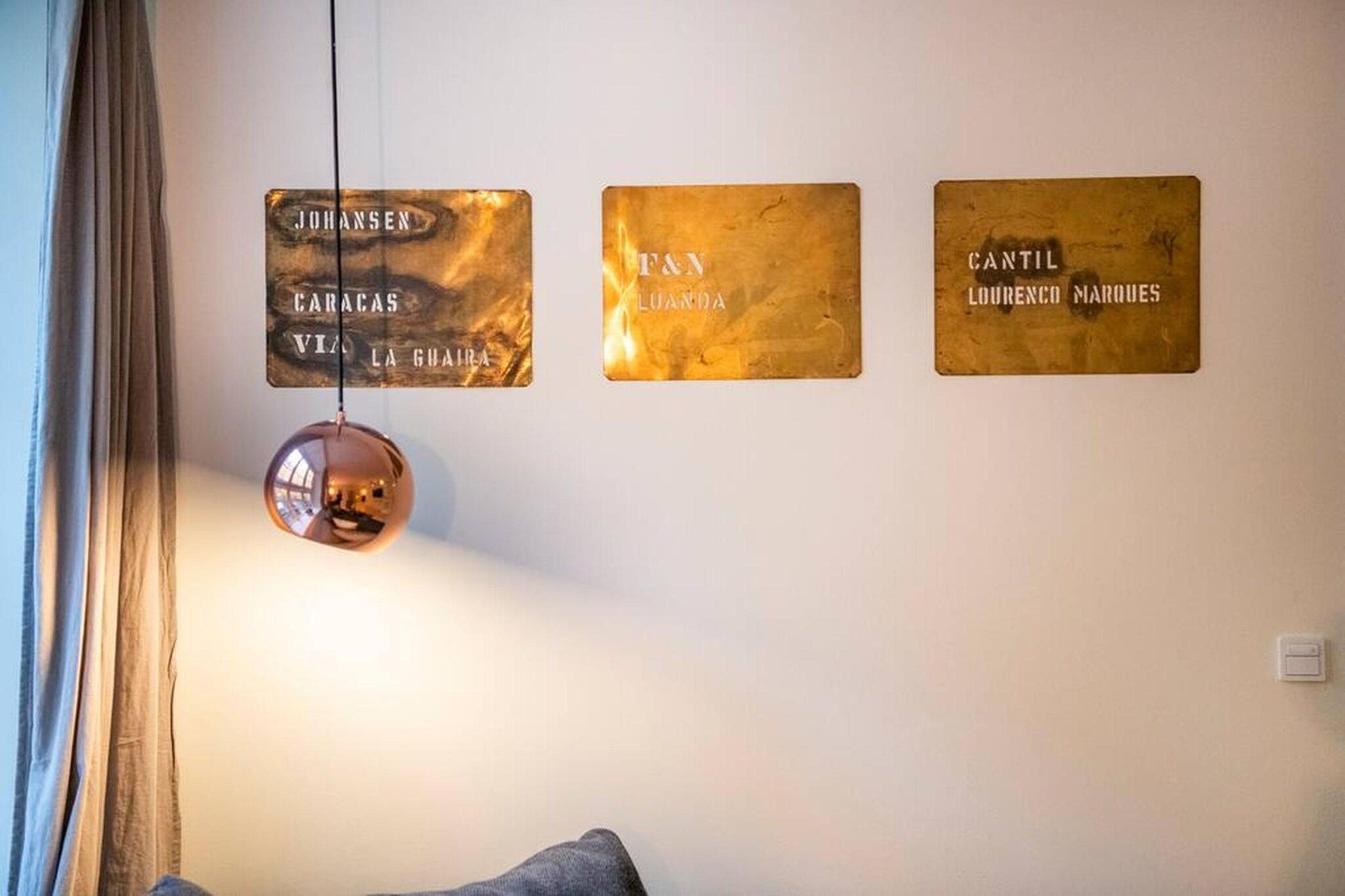 A wall with three plaques and a hanging spherical light fixture.
