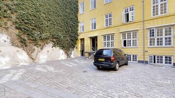 A car parked on a cobblestone street in front of a yellow building with multiple windows.