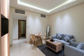 A modern living room with a sofa, coffee table, and dining area. - Maskan Alolya (Al Khobar)