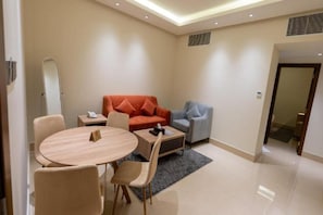 Una sala de estar moderna con una mesa redonda de madera, dos sofás y una pequeña mesita auxiliar.