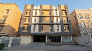 A multi-story building with a central entrance, balconies, and a sign indicating it is a serviced apartment complex. - Maskan Alolya (Al Khobar)