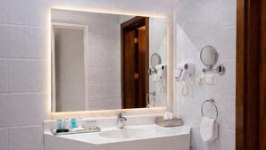 A modern bathroom with a large mirror, two sinks, and a towel rack. - Carawan Al Khaleej Hotel Olaya (Riyadh)