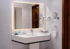 A modern bathroom with a large mirror, two sinks, and a towel rack. - Carawan Al Khaleej Hotel Olaya (Riyadh)