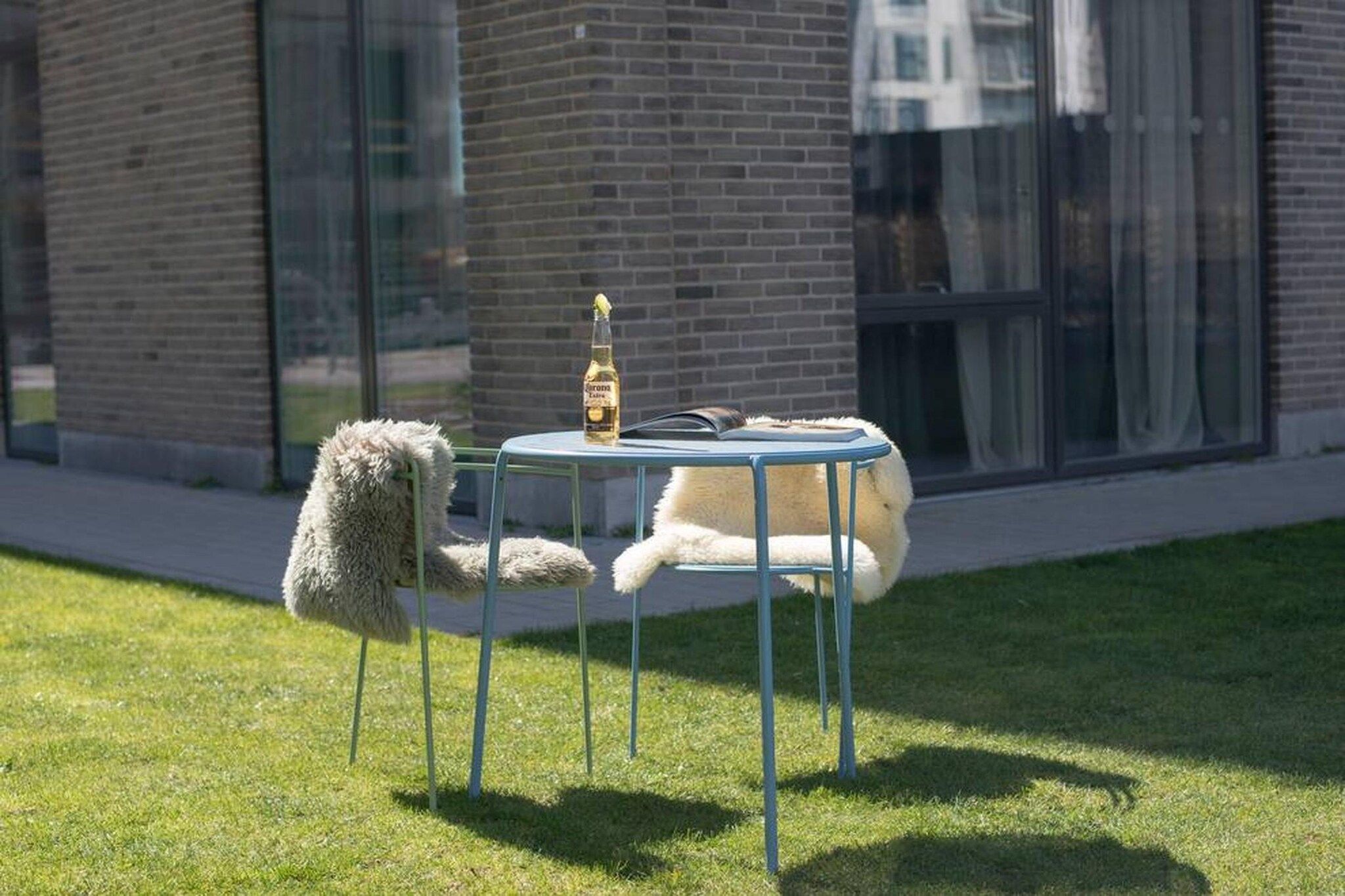 A white dog lying on a blue chair outside a building with a glass window.
