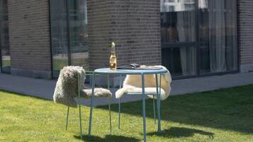 A white dog lying on a blue chair outside a building with a glass window.