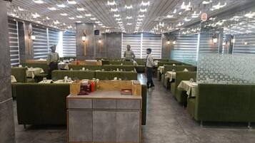 Um restaurante com assentos estofados verdes, um balcão central de atendimento e um teto com iluminação embutida.