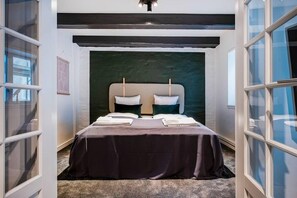 A bedroom with a bed, two bedside tables, a dark-colored bedspread, and a view through a window. - Residence Near Amalienborg Palace (København)