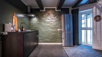 A modern kitchen with a stone backsplash, a built-in oven, and a stainless steel refrigerator.