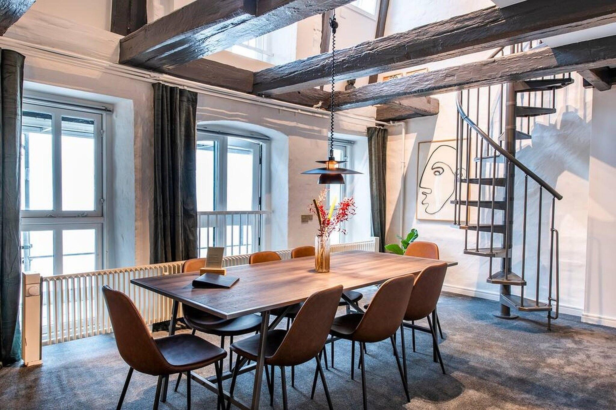 Un espace repas moderne avec une table en bois, des chaises et un vase rempli de fleurs.