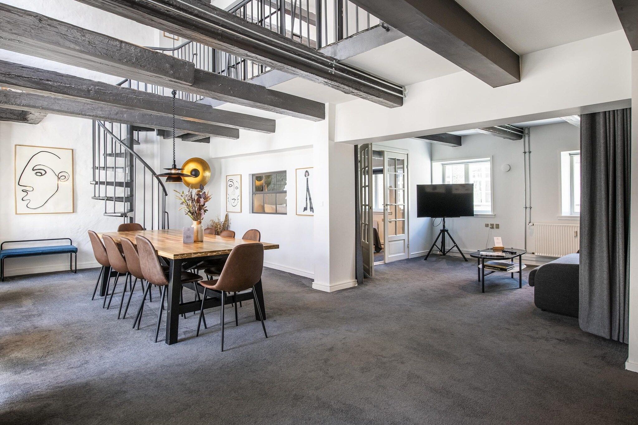 A spacious living area with a dining table, chairs, a sofa, and a television.