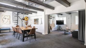 A spacious living area with a dining table, chairs, a sofa, and a television.