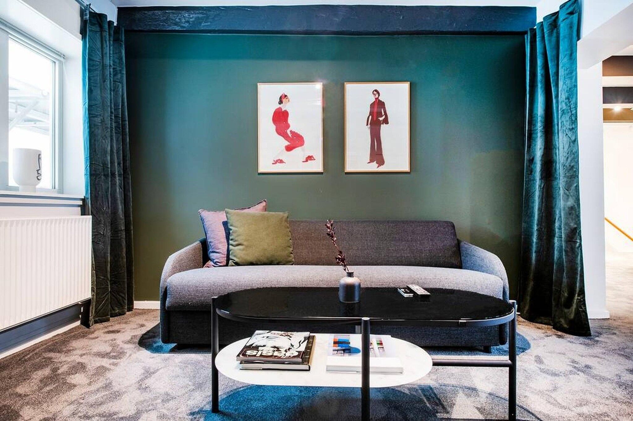 A modern living room with a grey sofa, a round coffee table, and two framed artworks on the wall.