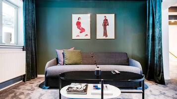 A modern living room with a grey sofa, a round coffee table, and two framed artworks on the wall.