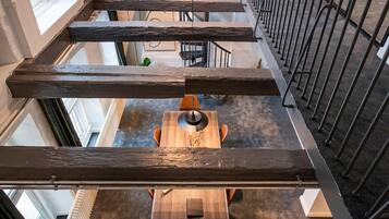 Een ruim interieur met een houten tafel en stoelen in het midden, omringd door een metalen leuning.