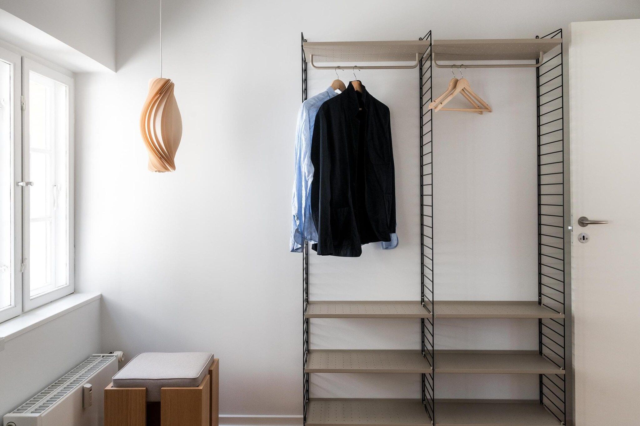 Ein begehbarer Kleiderschrank mit offenen Regalen, einer Kleiderstange und einem Heizkörper.
