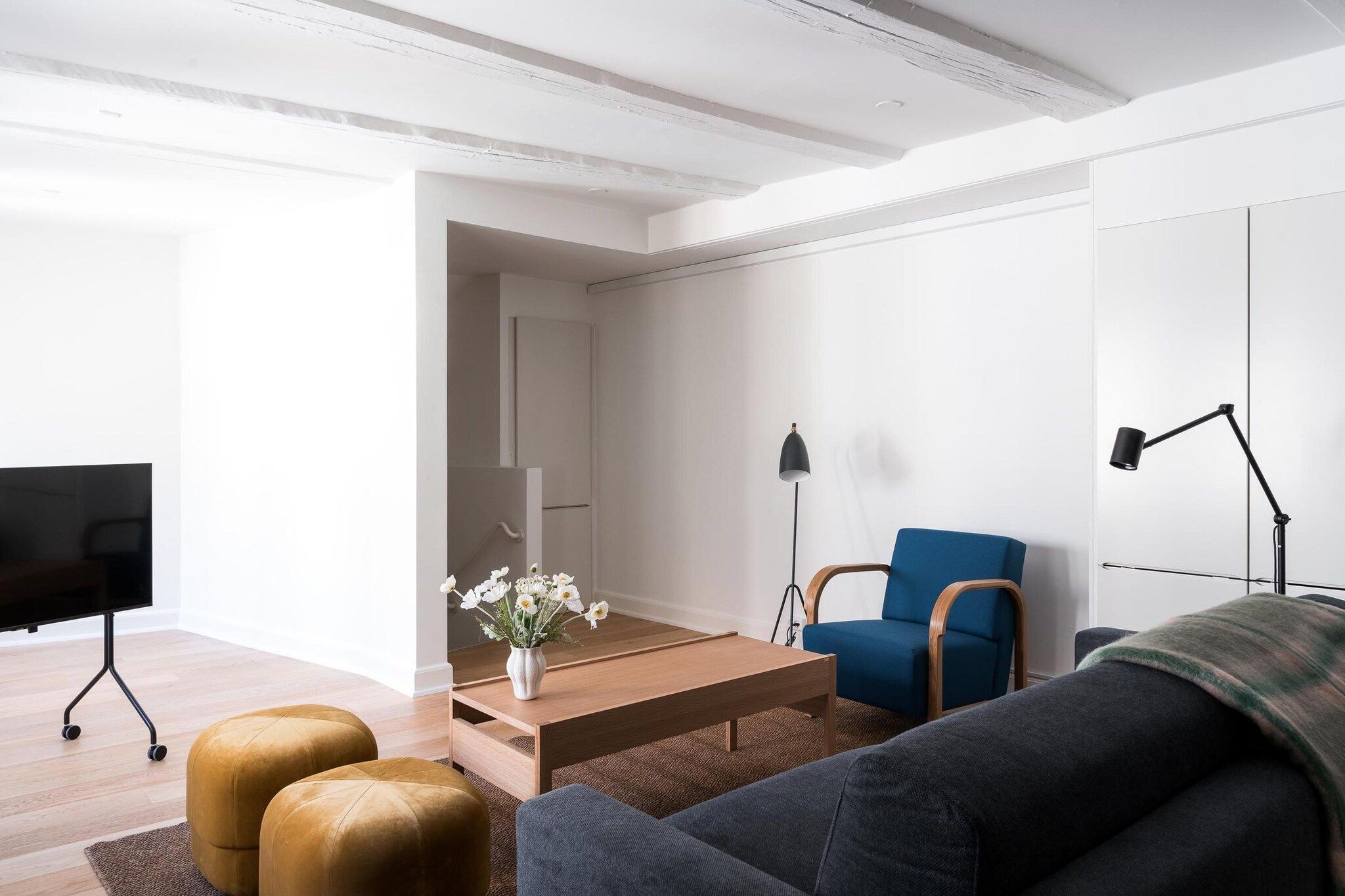 Ein modernes Wohnzimmer mit Flachbildfernseher, blauem Sessel, Holztisch und einer Couch.
