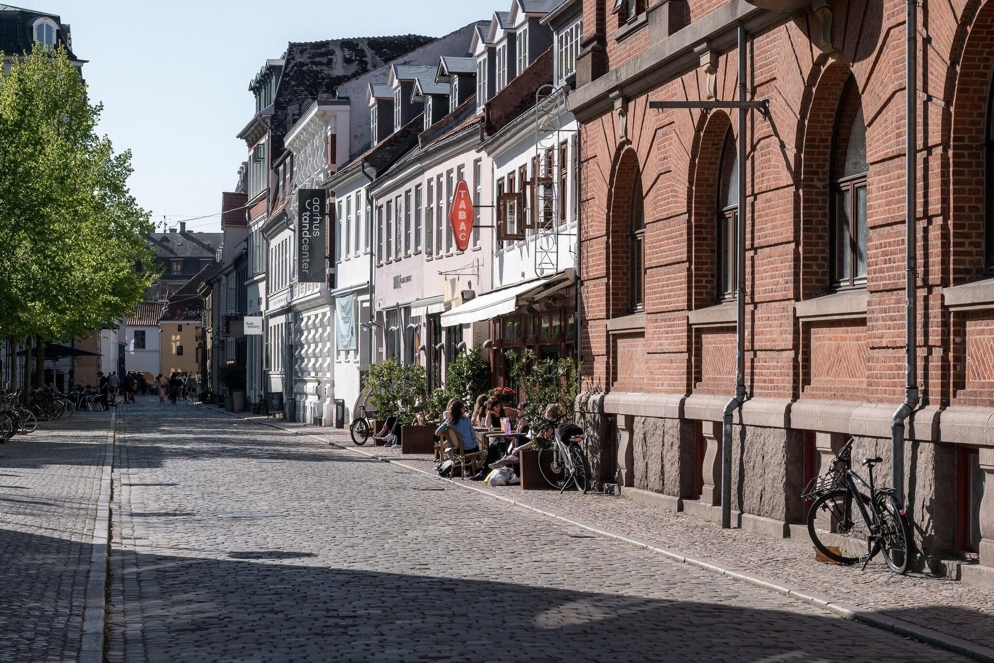 Een straat met keien omzoomd door historische gebouwen, waarvan sommigen bewegwijzerd zijn.