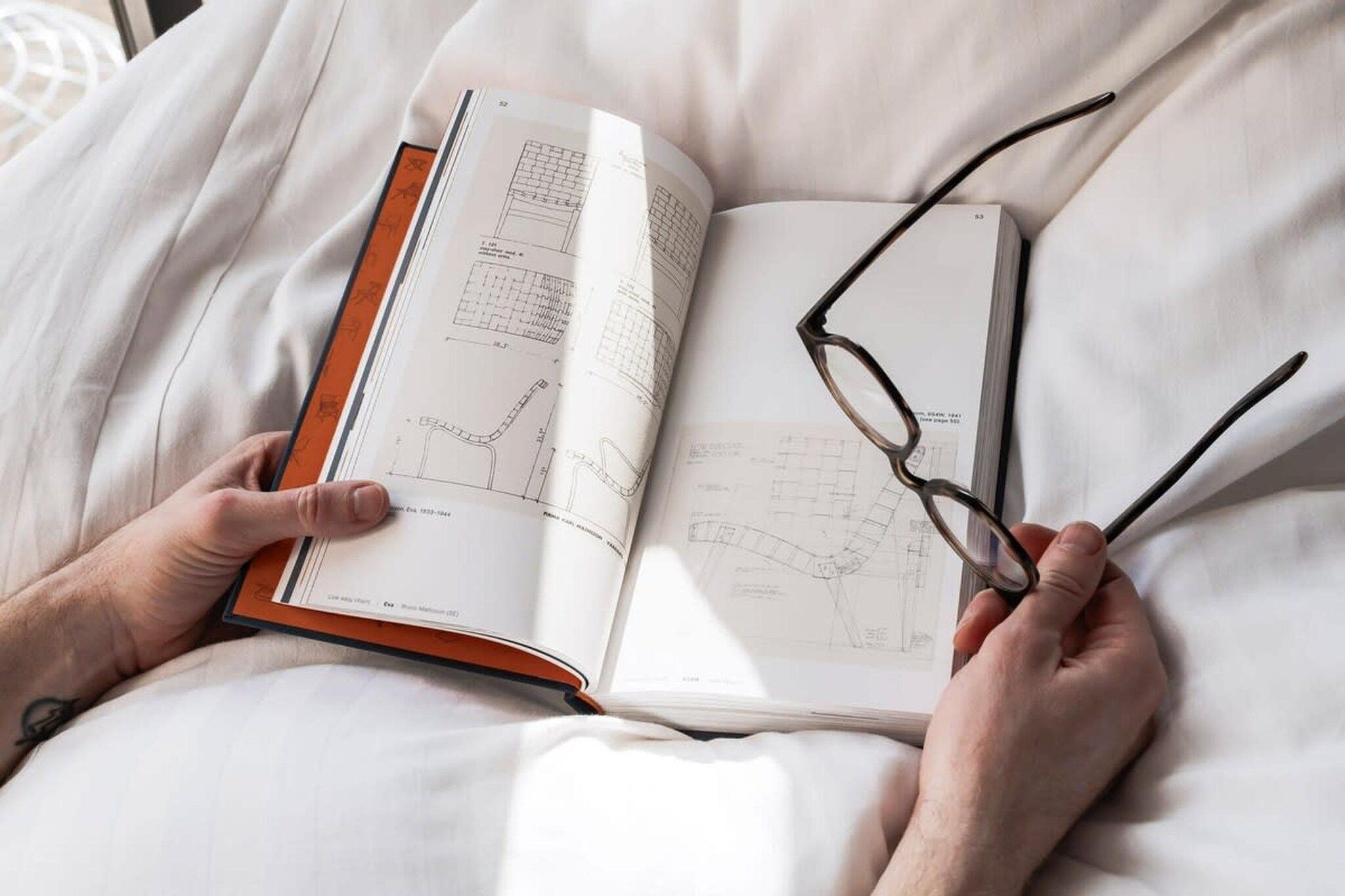 A person lying on a bed with a book open in front of them.