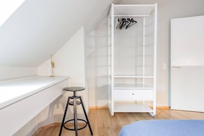 A white room with a loft bed, a small stool, a white wardrobe with hanging space, and a door. - Family Retreat Near Kongens Nytorv (København)