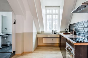 A modern kitchen with a window, a radiator, and a stove. - Family Retreat Near Kongens Nytorv (København)