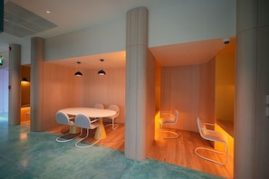 A modern interior with a round table and chairs, wooden flooring, and a ceiling with recessed lighting. - Go Hotel Ban Chang (Ban Chang)