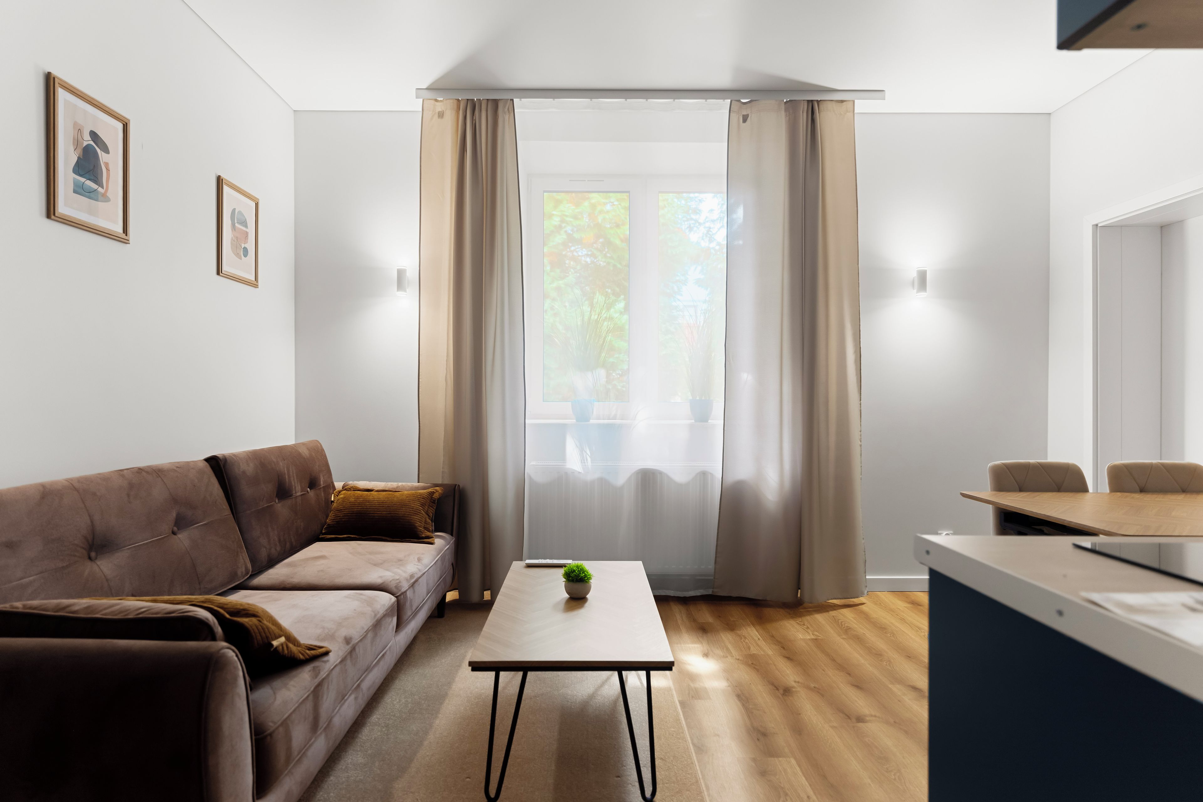 A modern living room with a sofa, a coffee table, and a dining area with a table and chairs.