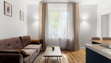 A modern living room with a sofa, a coffee table, and a dining area with a table and chairs.