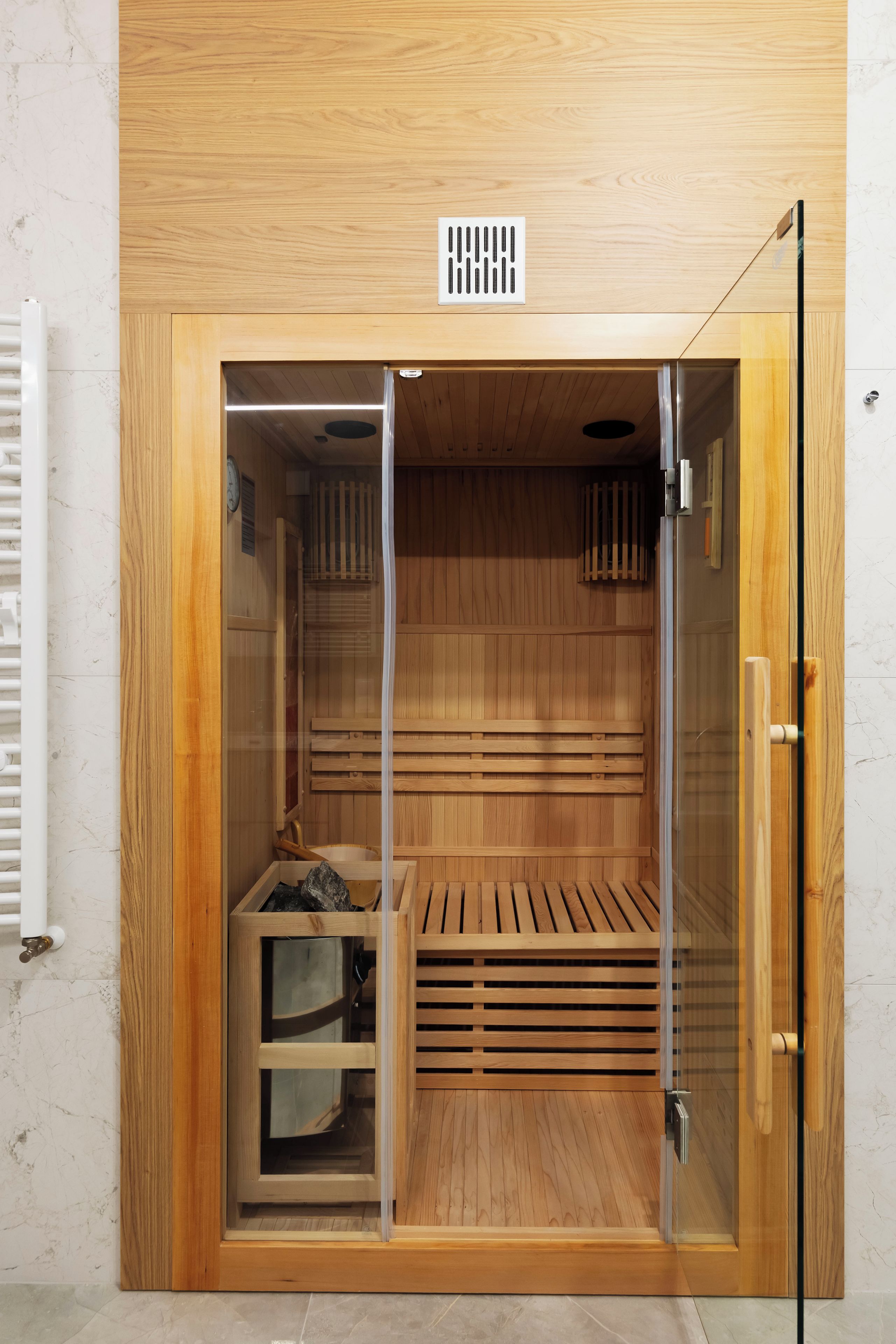 A sauna with wooden walls, a bench, and a glass door.