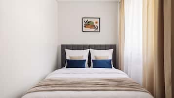 Una cama bien hecha con cabecera, dos almohadas y una colcha.