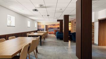 A conference room with a long table, chairs, a projector, and a mural of a sunset.