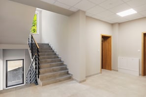 A staircase with a wooden handrail and grey steps leading to a landing.