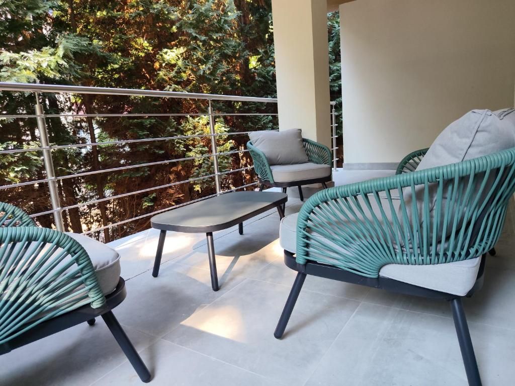 Ein Balkon mit Korbmöbeln, einem kleinen Tisch und Blick auf Bäume.