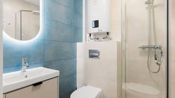 A modern bathroom with a white sink, a toilet, and a glass-enclosed shower.