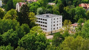 A multi-story building surrounded by dense greenery, with a flat roof and multiple windows. - Edenhall Apartments & SPA (Duszniki-Zdrój)