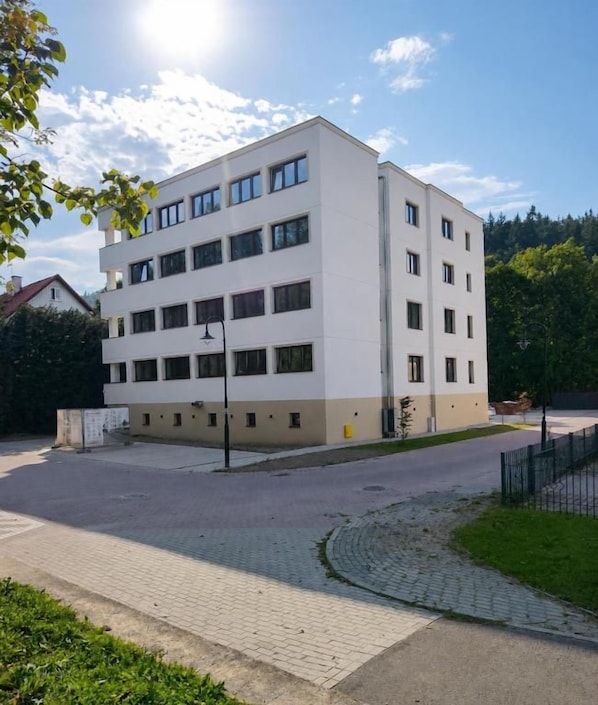 A multi-story building with a flat roof, rectangular windows, and a paved courtyard.