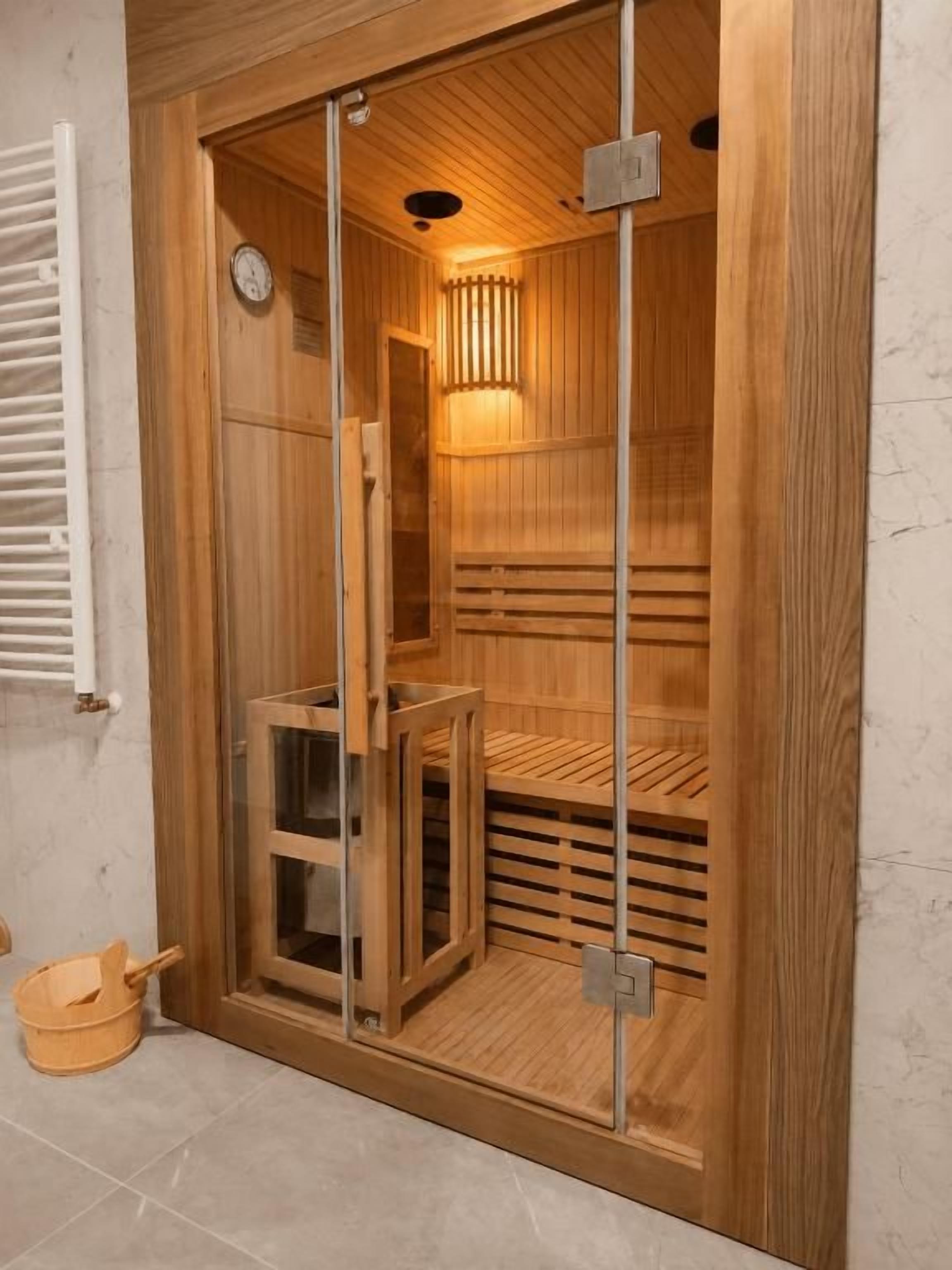 A sauna with a wooden interior, glass door, and a bench.