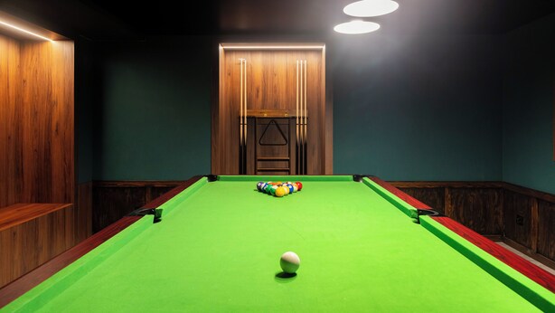 A pool table with balls in the center, surrounded by wooden paneling and a green felt surface. - Edenhall Apartments & SPA (Duszniki-Zdrój)