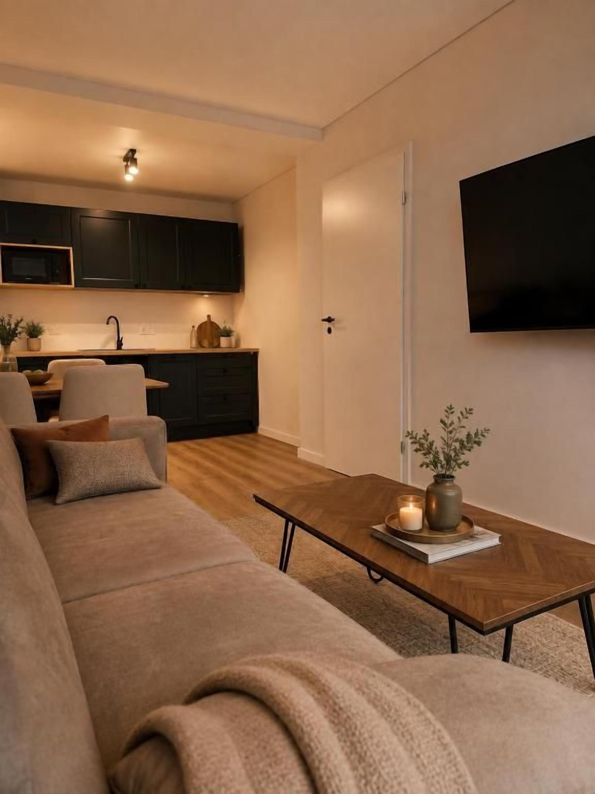 Ein modernes Wohnzimmer mit einer Couch, einem Couchtisch und einem an der Wand befestigten Flachbildfernseher.