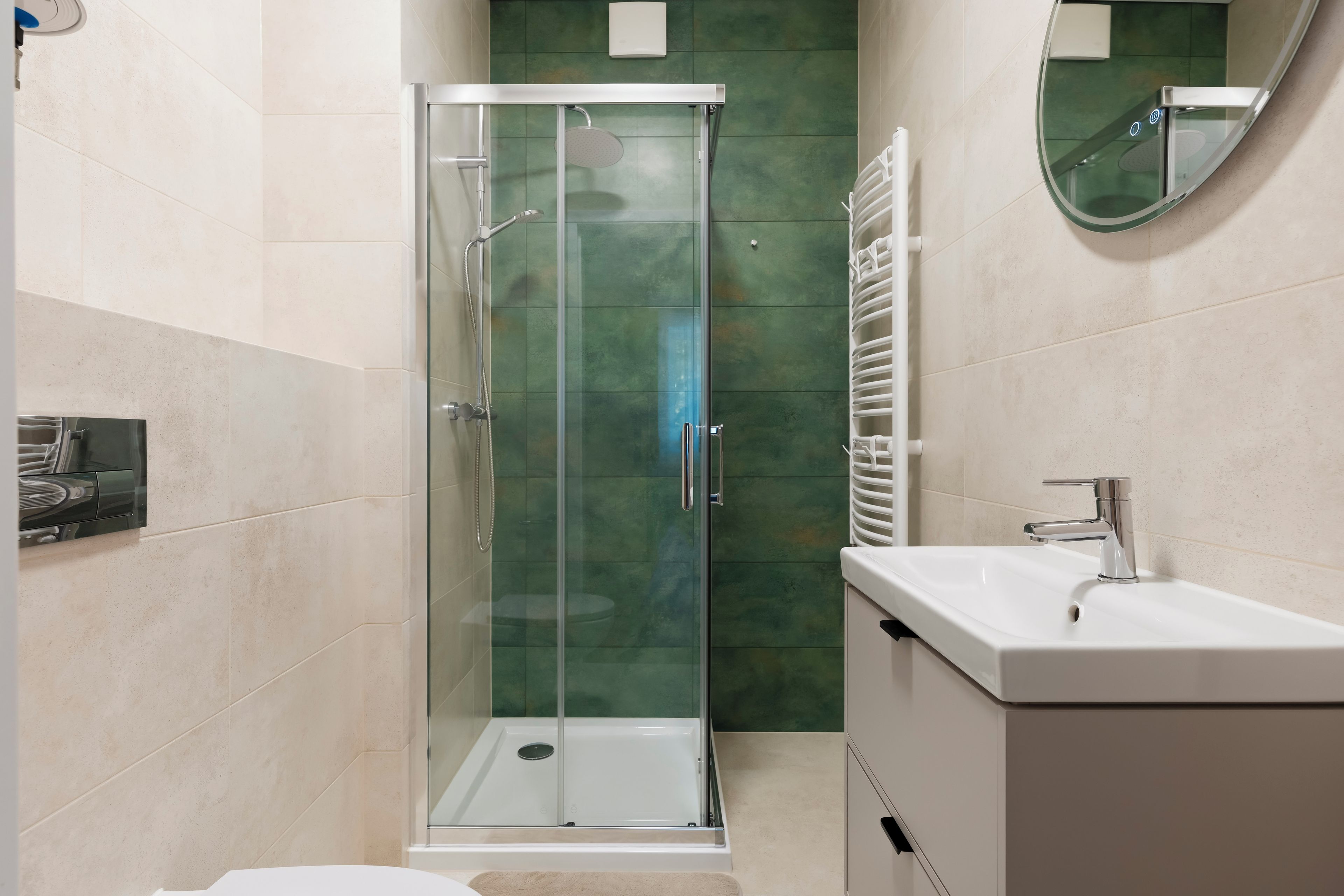 Un baño moderno con ducha de vidrio, lavabo blanco y espejo.