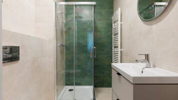 Un baño moderno con ducha de vidrio, lavabo blanco y espejo.