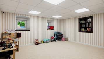 Una habitación con pared a rayas, una estantería, una ventana y una tienda de juguetes.