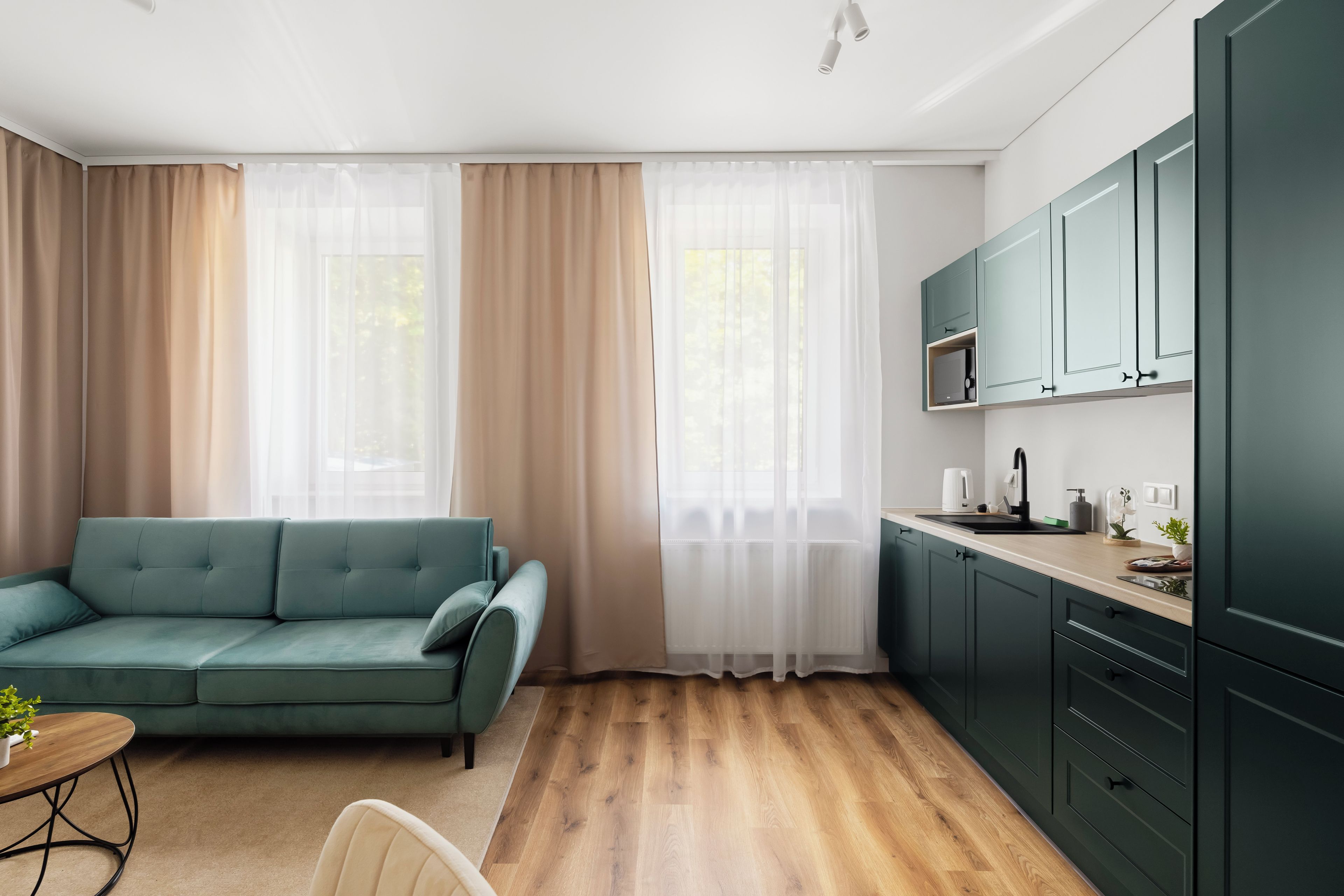 Een moderne woonkamer met een bank, een eethoek met een tafel, en een keuken met kastjes.