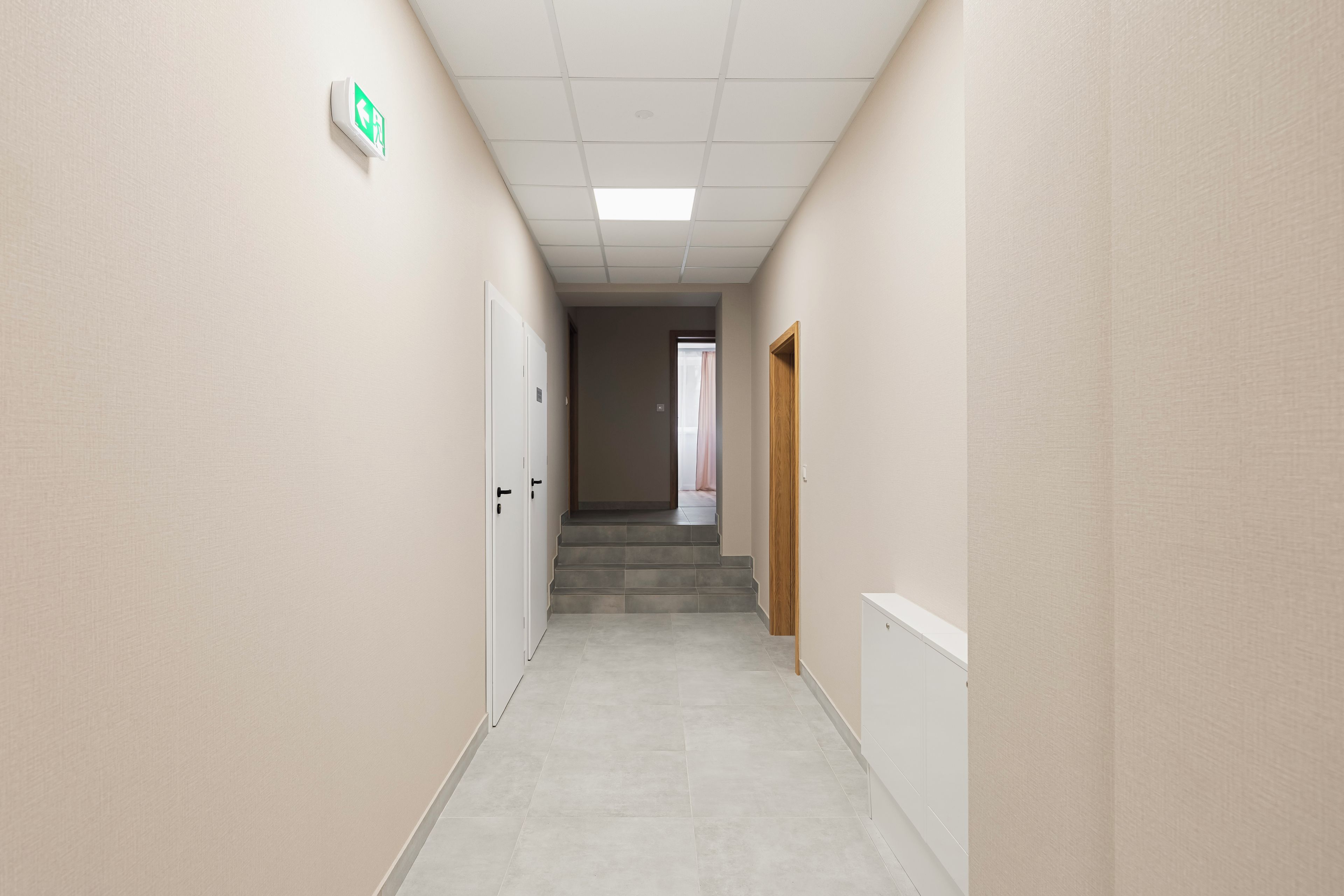 A corridor with a ceiling light, a door with a handle, and a staircase leading to another room.
