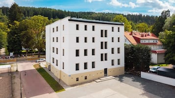 A multi-story building with a flat roof, rectangular windows, and a paved ground area.