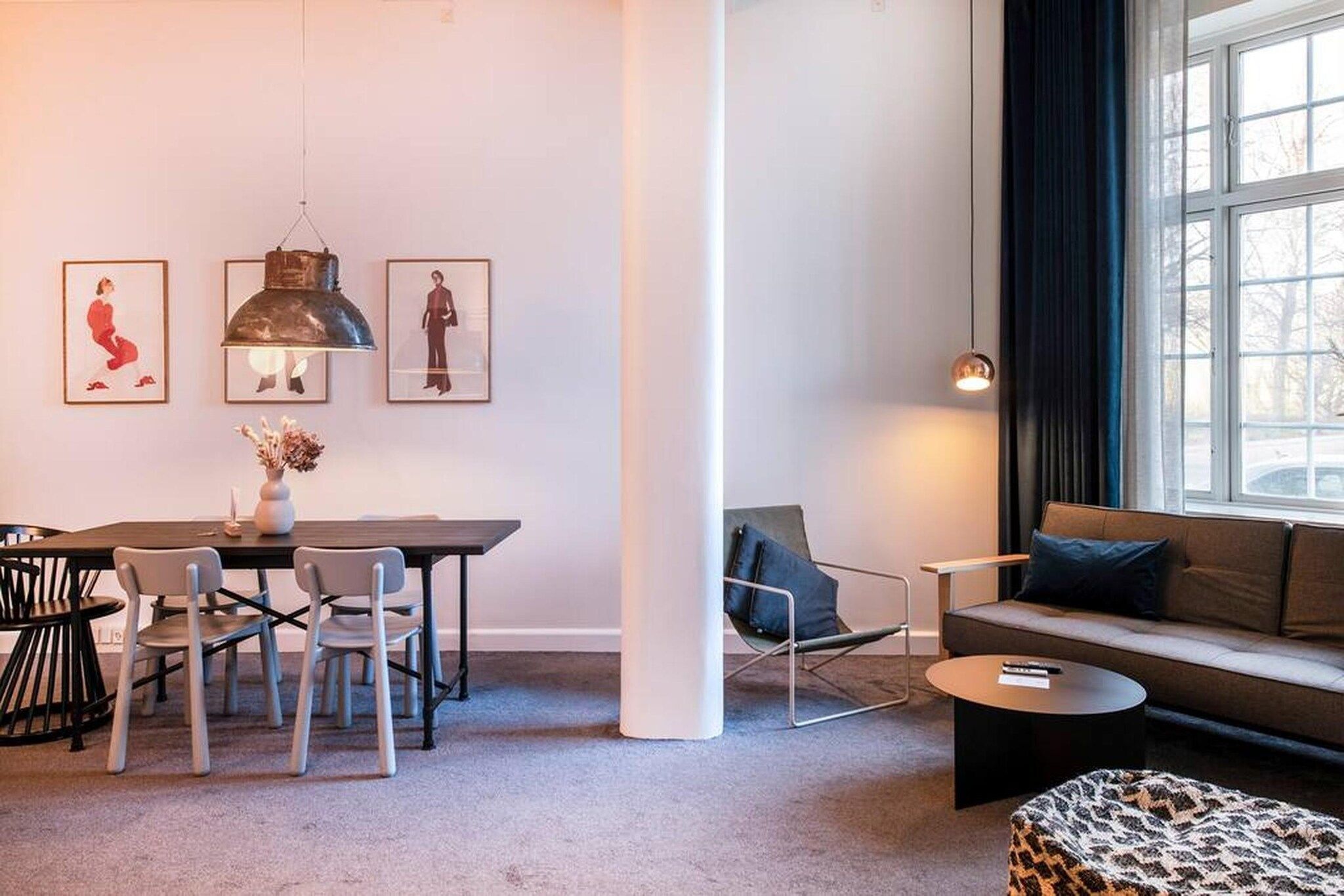 A modern living room with a dining area, a sofa, a coffee table, and a window with curtains.