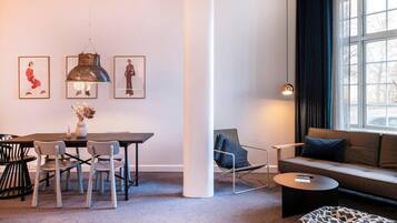 A modern living room with a dining area, a sofa, a coffee table, and a window with curtains.