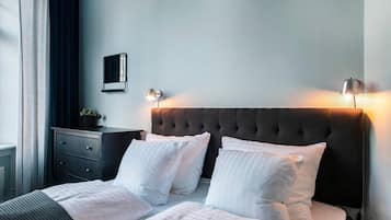 A hotel room with a large bed, two bedside tables, a dresser, and a wall-mounted mirror.