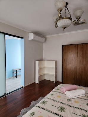 Ein Schlafzimmer mit einem Bett, einem Eckschrank, einer Einbauschränken, einem Deckenventilator und einer Klimaanlage.