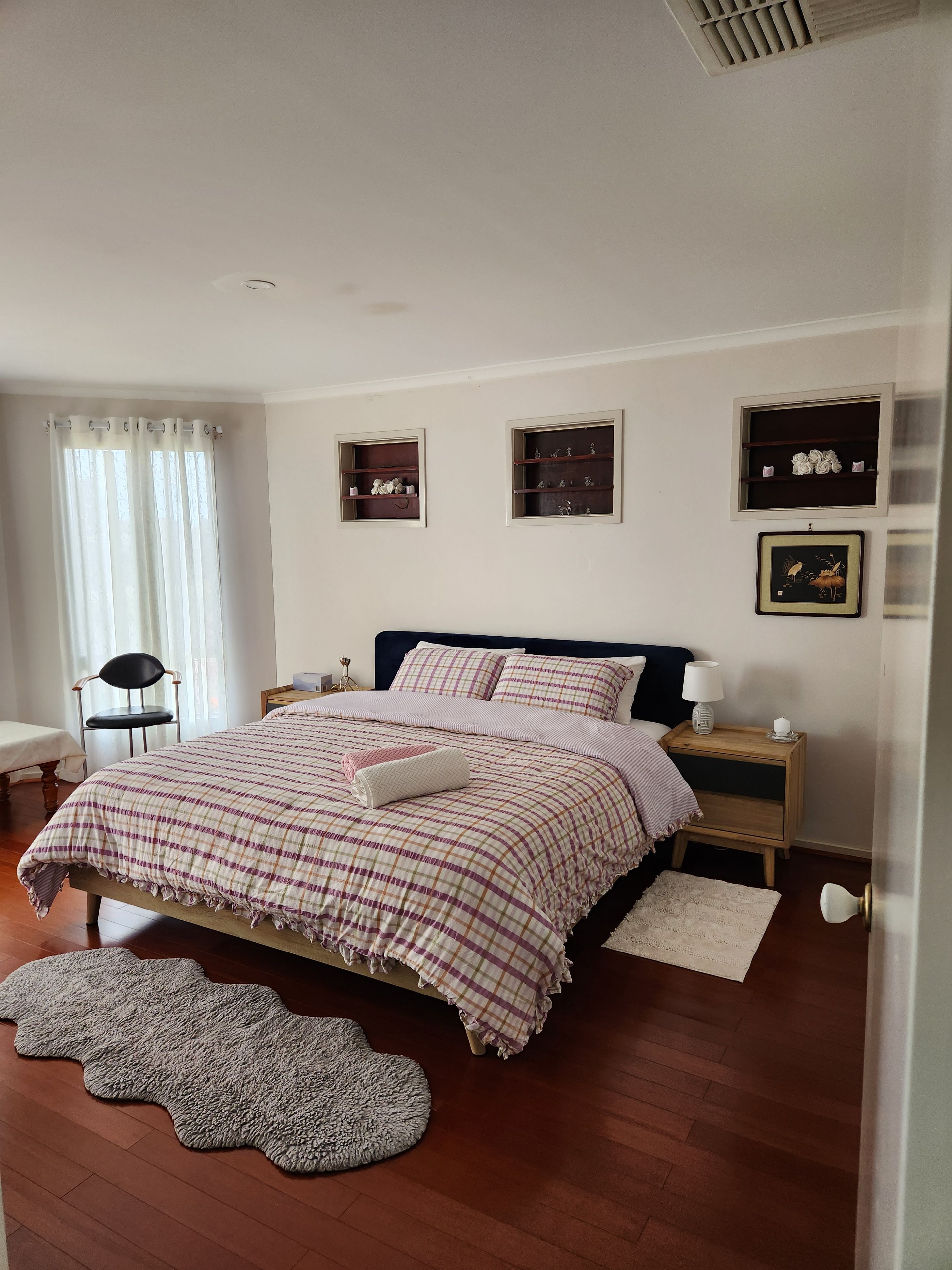 A bedroom with a bed, bedside tables, a chair, and a window with curtains.