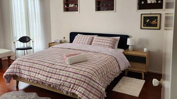 A bedroom with a bed, bedside tables, a chair, and a window with curtains.